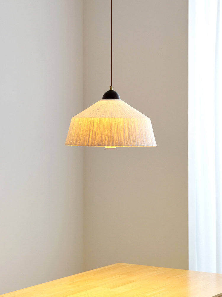 In a plain corner above a wood table's edge, this Clérachic pendant's beige rice paper shade glows warm.