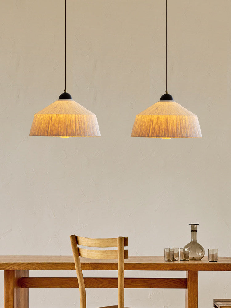 Two of these Clérachic pendants glow warm above a wood table set with a chair and a glass decanter.