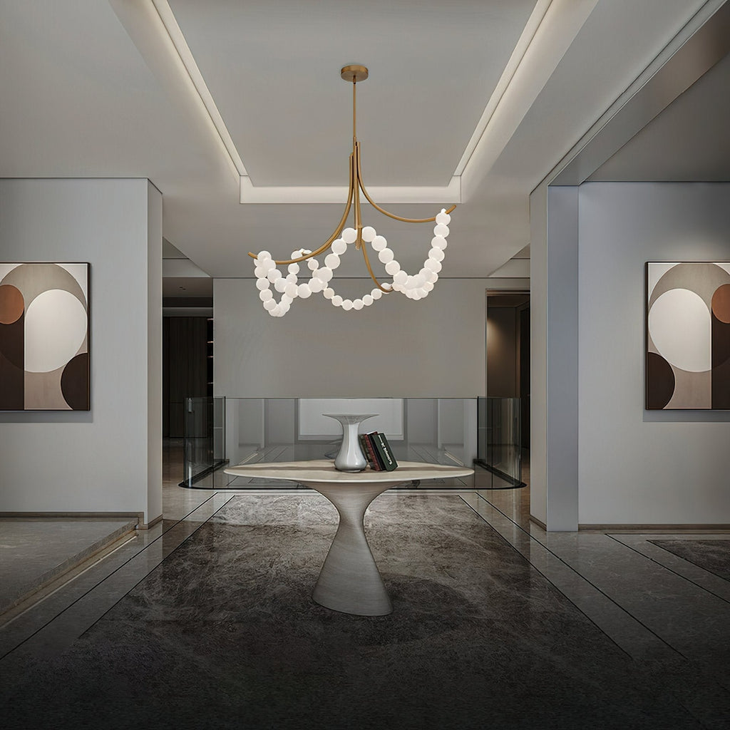 Gold Parel chandelier lit over an oval stone table in a dark hallway hung with abstract art