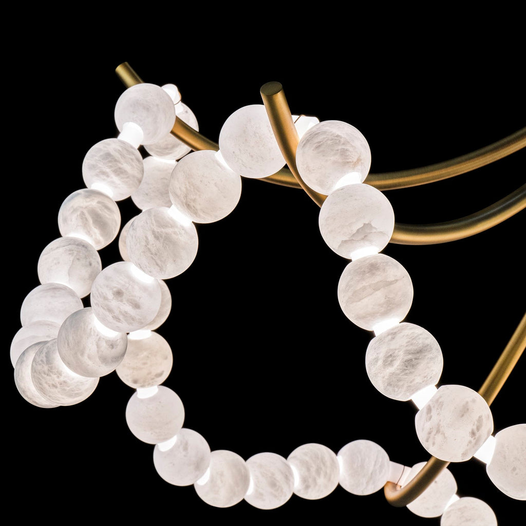 Macro of the gold arms and glowing alabaster beads, showing the stone's soft grey veining