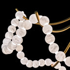 Macro of the gold arms and glowing alabaster beads, showing the stone's soft grey veining