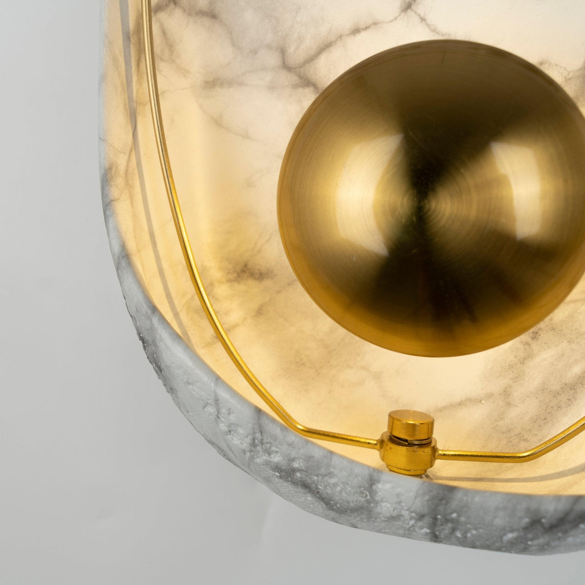 Close crop of the brass orb top right, with the hoop and its brass collar over the rough lower rim.