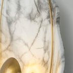 Close crop of grey veining across the marbled face, the brass hoop down one side and the lit orb below.