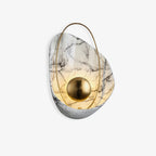 Marbled shell wall sconce in white, lit behind its brass orb, shown against a plain white ground.