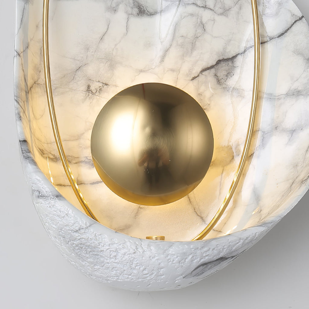 Close crop of the polished brass orb reflecting the room, the lit shell and rough rim behind it.