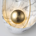 Close crop of the polished brass orb reflecting the room, the lit shell and rough rim behind it.