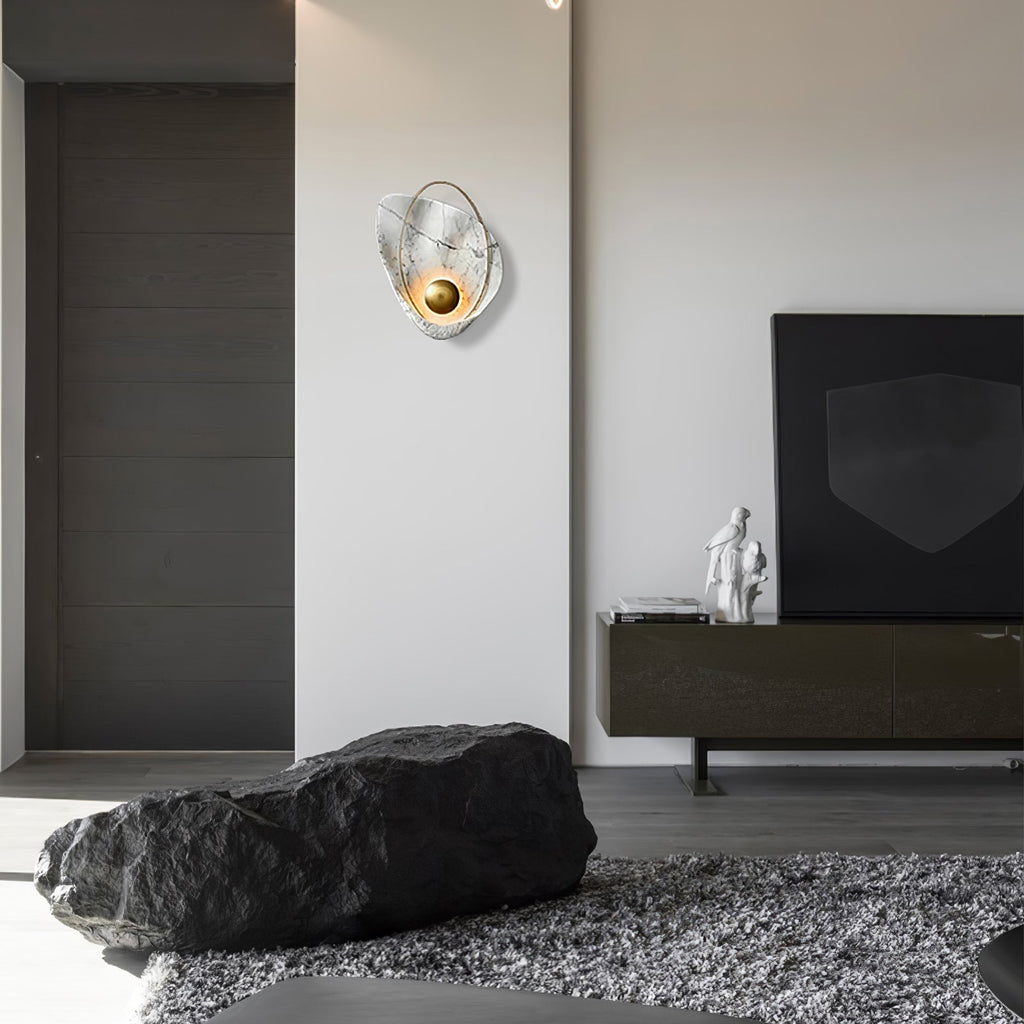 The lit sconce on a white wall in a living room, with a low media unit and a dark stone bench.