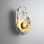 Three-quarter view of the lit sconce, showing the depth of the cupped shell and its rough lower rim.