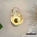 Lit sconce on a pale wall, with a spray of dried branches and a white stone ornament alongside.