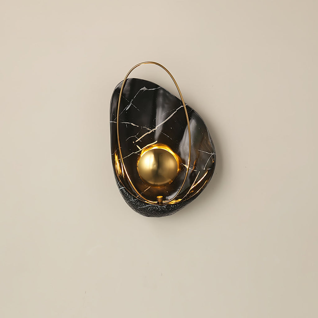 Black marbled sconce lit straight on against a beige wall, white veining across the dark shell.