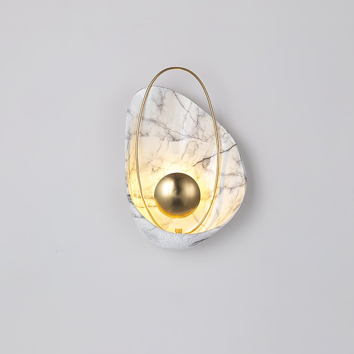 Lit white marbled sconce on a pale grey wall, the warm glow rising through the shell above the orb.