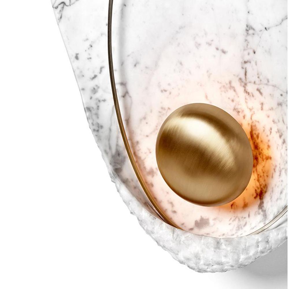 Close crop of the brass orb with warm light spilling around it across the marbled face.