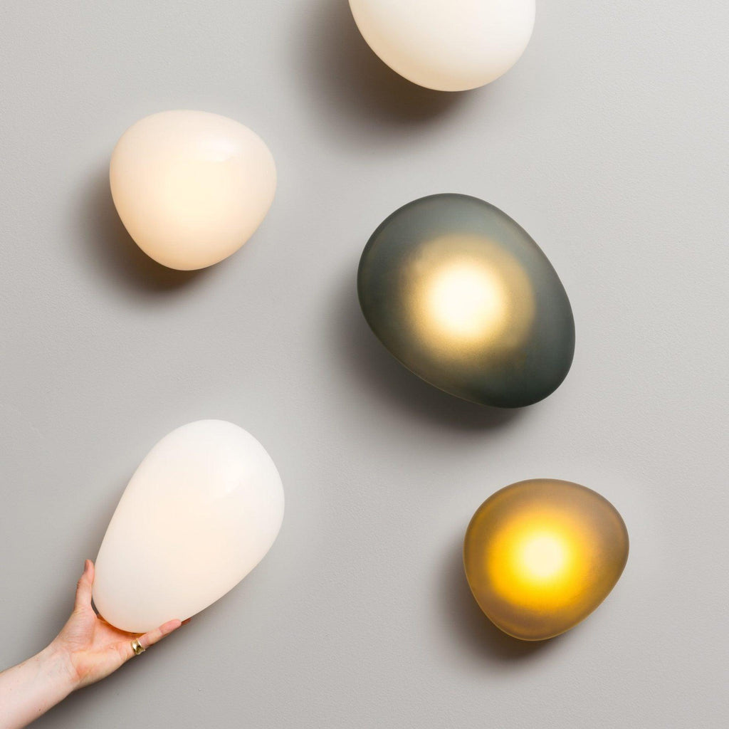 Pebble wall lamp glowing gently as a quiet focal point