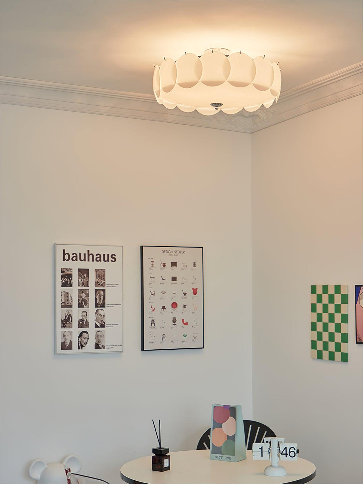 A lit Clérachic ceiling light hangs in a playful room corner with pop-art prints and a small round table.