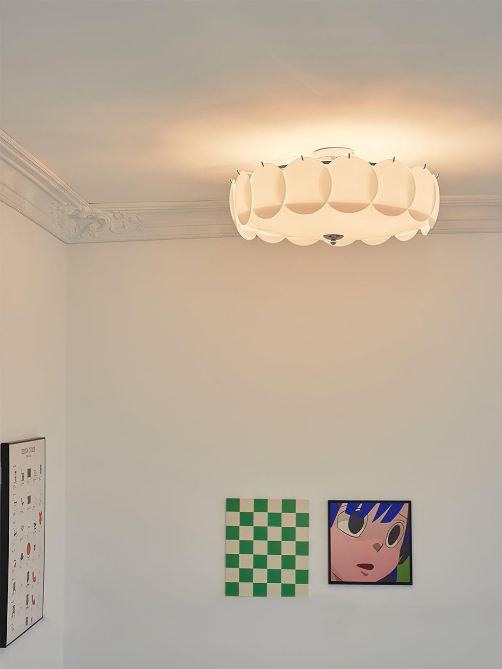 A lit Clérachic ceiling light sits against a corniced ceiling above colourful checkerboard and pop-art prints.