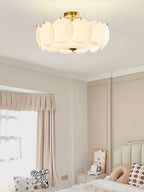 This Clérachic ceiling light glows warm in a bedroom corner, above a window dressed with soft pink curtains.