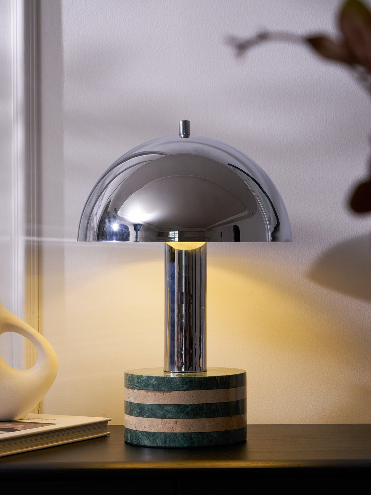 Tightly cropped shot of the Clérachic lamp on the dark cabinet, the dome cut off at the top and the vase visible below.