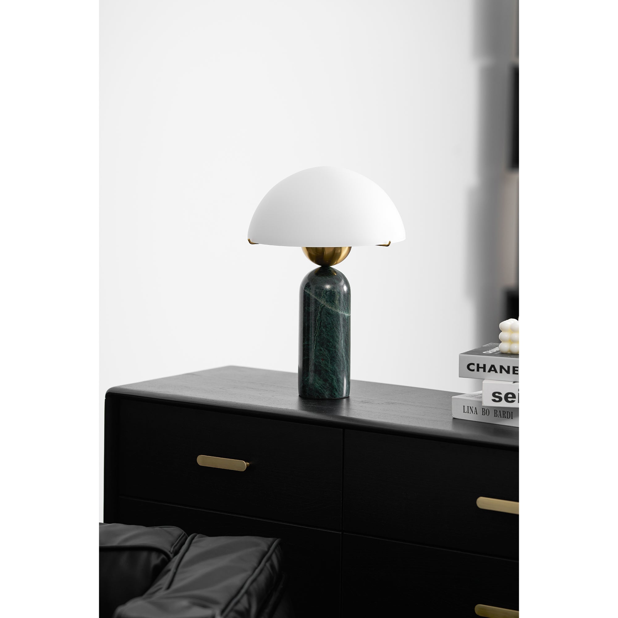 Green marble Veviniel lamp unlit on a black dresser, seen from across the room.