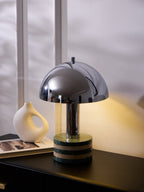 Clérachic lamp lit beside the vase and book on the dresser, daylight coming through the window behind it.