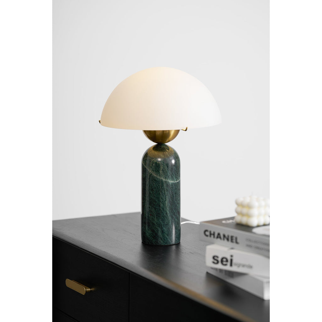 Angled view of the green marble Veviniel lamp lit on a black oak dresser.