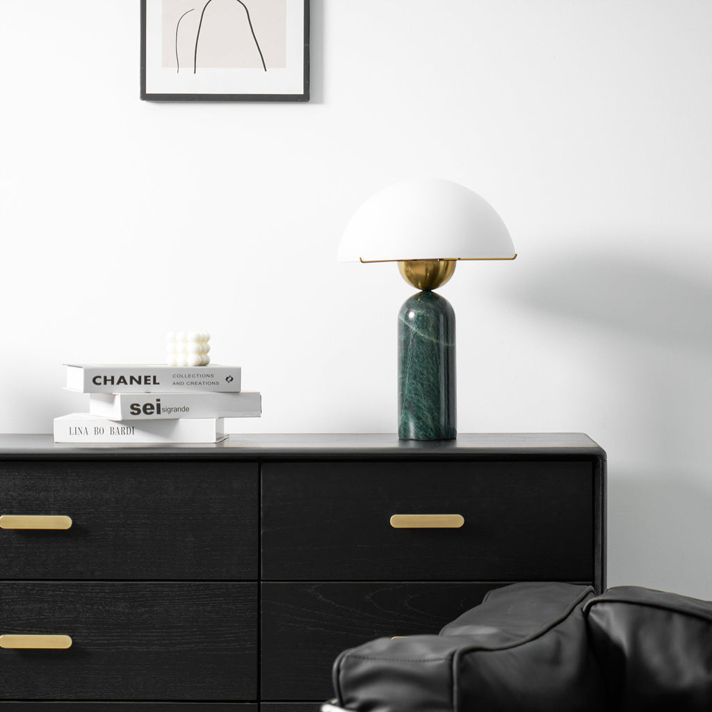 Unlit green marble Veviniel lamp on a black dresser below a framed line drawing.