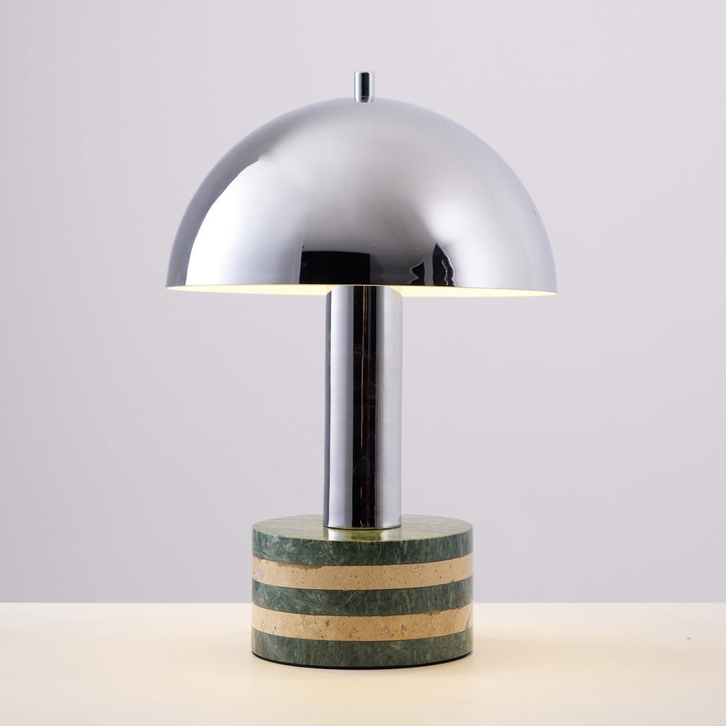 Another straight-on shot of the lit Clérachic lamp on the grey backdrop, light spilling from under the dome's edge.