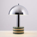 Another straight-on shot of the lit Clérachic lamp on the grey backdrop, light spilling from under the dome's edge.