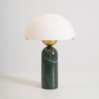 Studio shot of the green marble Veviniel lamp, brass sphere joining the shade to the stone column.