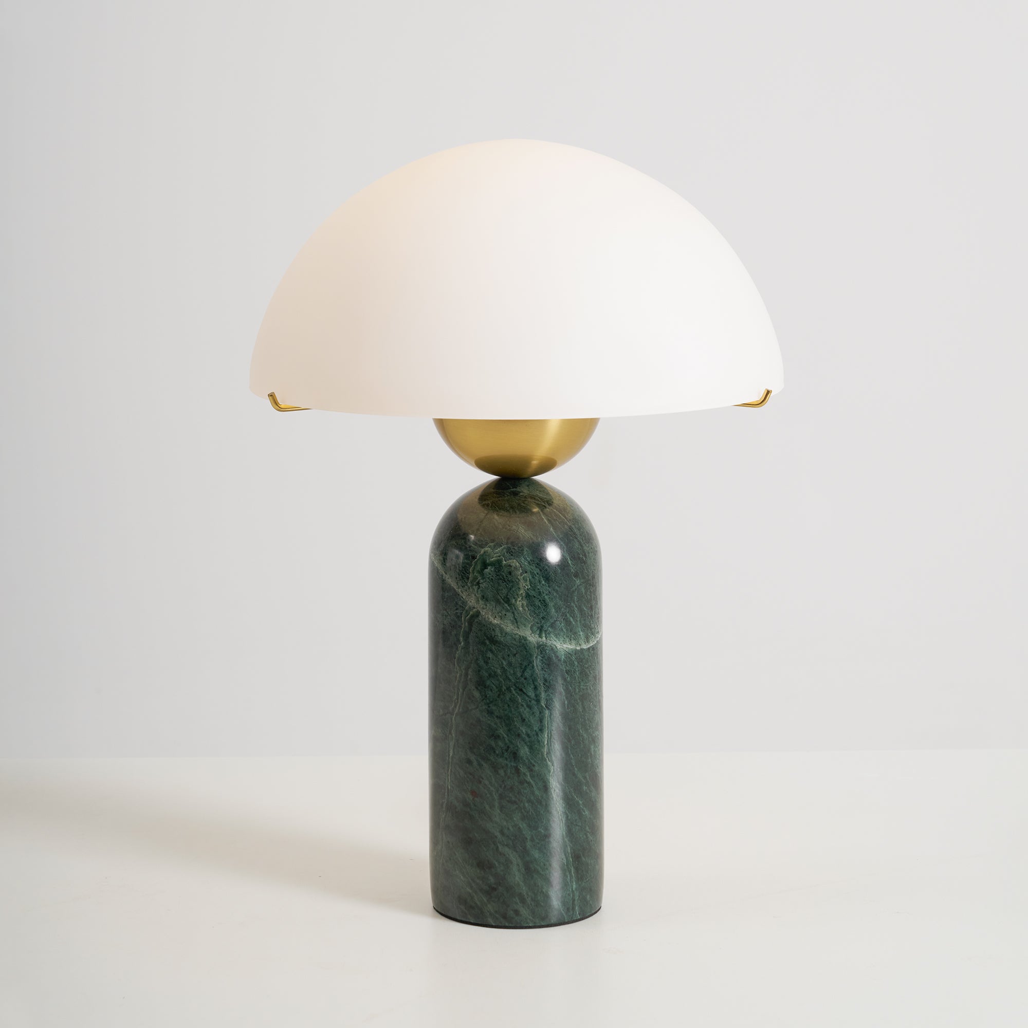Studio shot of the green marble Veviniel lamp, brass sphere joining the shade to the stone column.