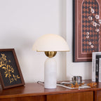 Veviniel lamp on a wooden sideboard seen slightly from below, brass shade rim edge in view.
