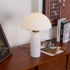 Veviniel lamp angled on a walnut sideboard next to coffee-table books and a small silver cup.
