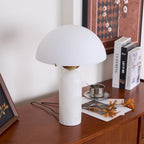 Veviniel lamp with a crisp white shade on a teak sideboard, angled beside books and a silver cup.