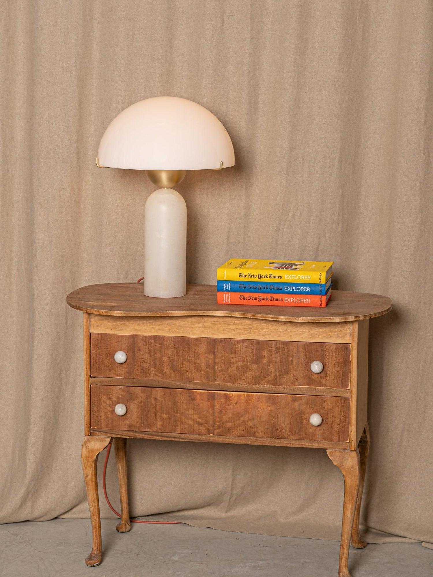 Full-length view of the Veviniel lamp on an antique two-drawer chest, red flex cord trailing to the floor.