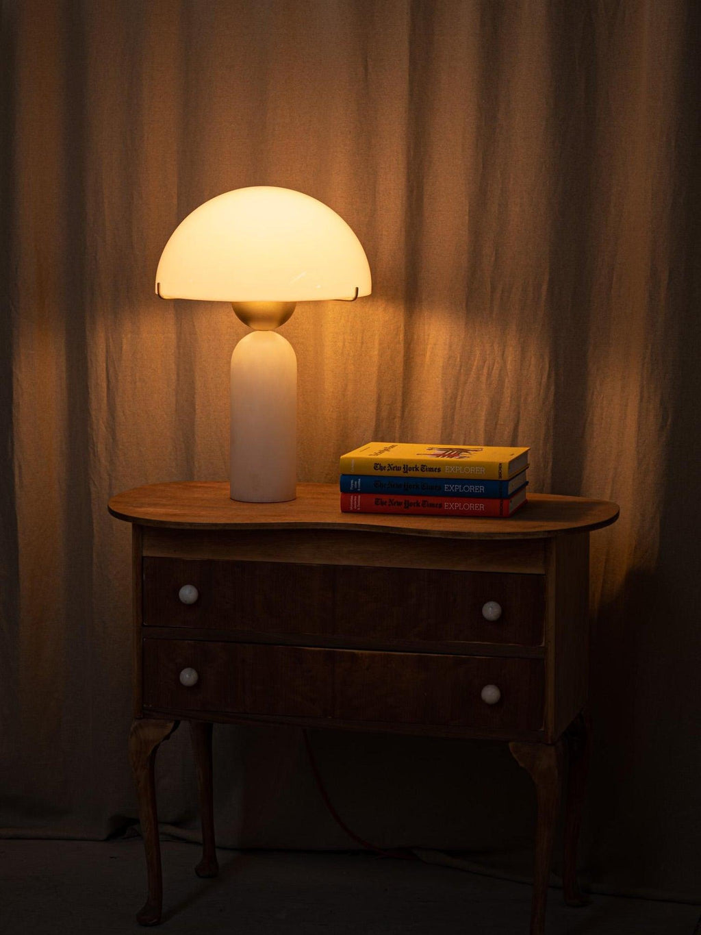 The Veviniel lamp switched on in a darkened room, its dome glowing warm above the wooden chest.