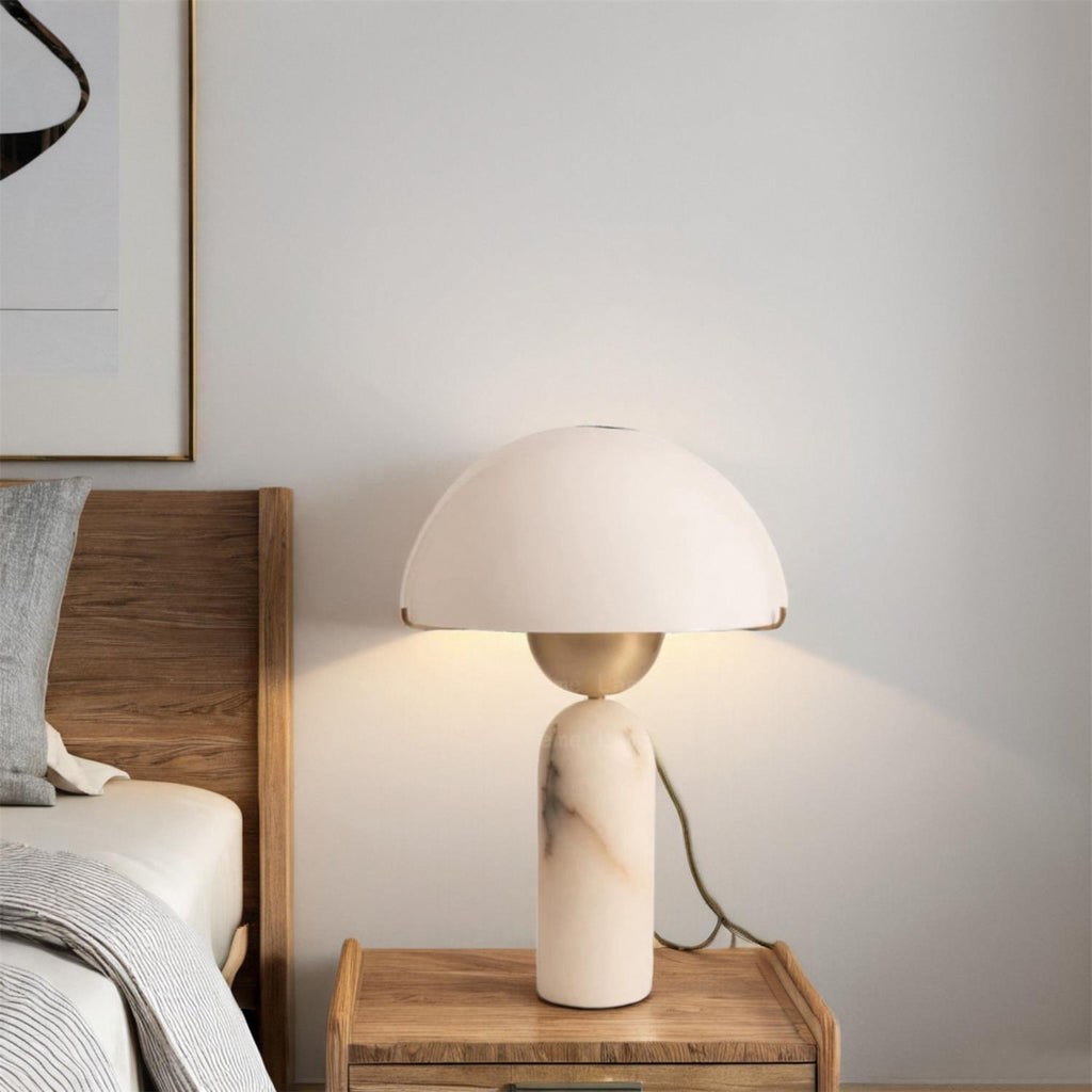 Veviniel lamp lit on a wooden bedside table, warm light washing the wall behind the headboard.