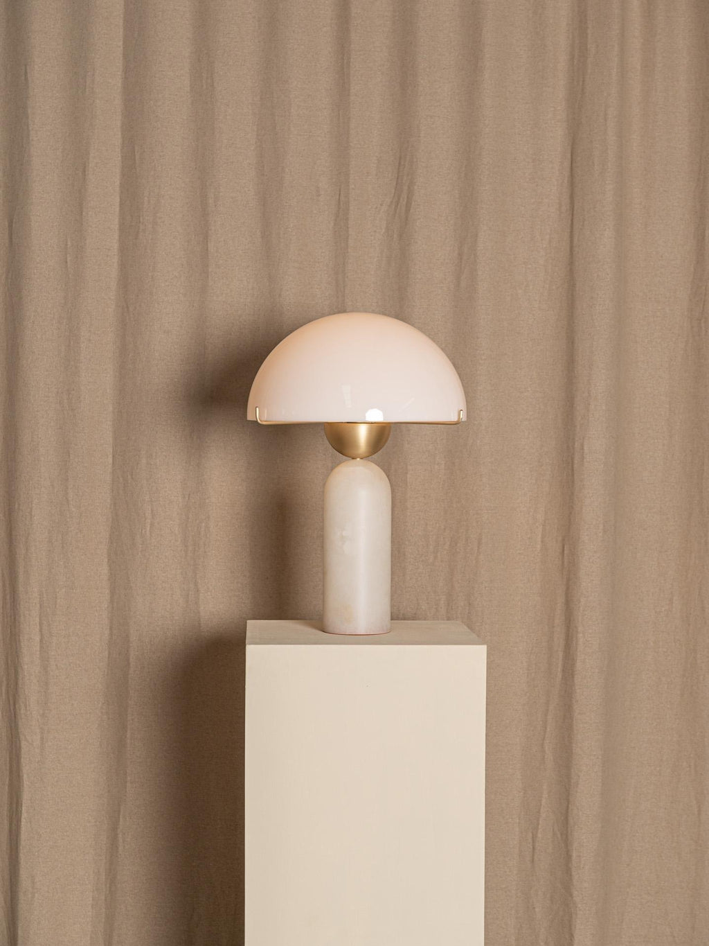 Veviniel lamp displayed on a pale plinth against a draped linen backdrop, shown at full height.