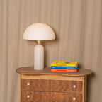 Veviniel lamp styled on a vintage wooden chest beside a stack of art books, unlit against a linen backdrop.