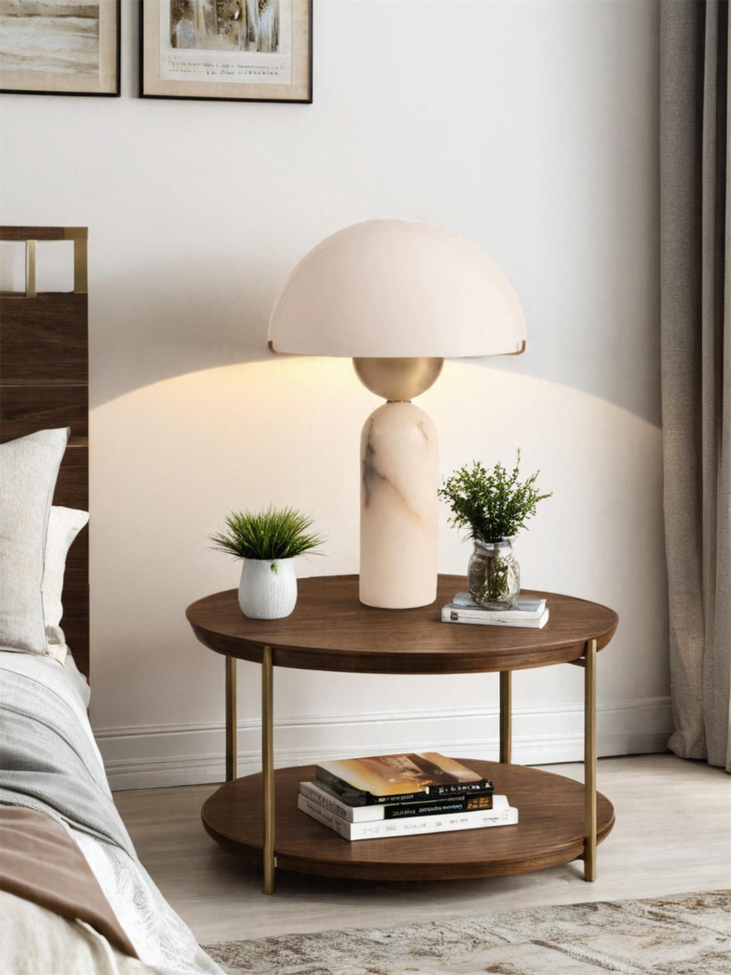 Veviniel lamp lit on a round walnut side table by a bed, with small plants either side of the stone base.