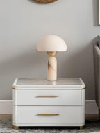 The Veviniel lamp seen from across the bedroom on a lacquered nightstand, showing its compact scale.