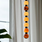 Warm light glows through the varied stone tones of this Clérachic pendant against a sheer curtain.