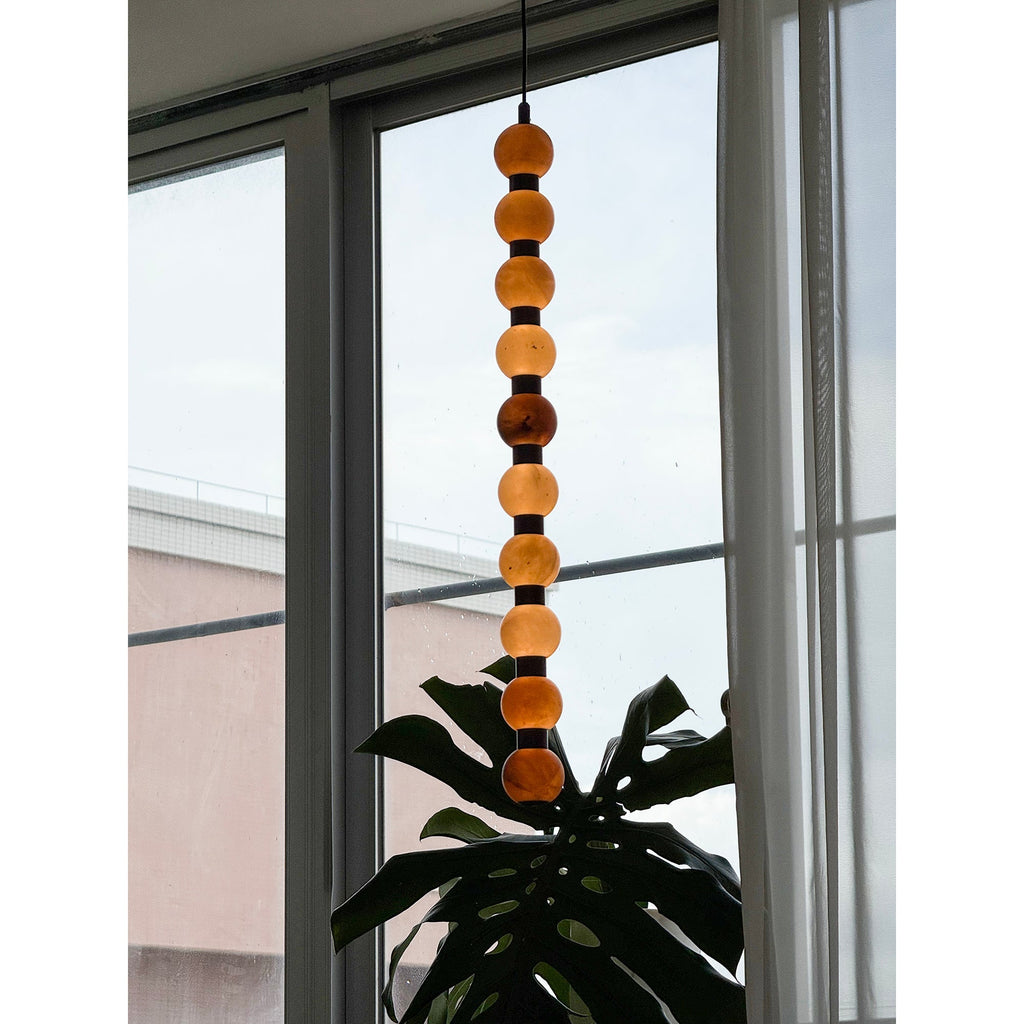 Overlooking nearby rooftops, this Clérachic alabaster sphere pendant glows warm against the window.