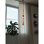 In dimmer light, this Clérachic pendant's spheres glow softly beside a curtained window and a wall of round discs.