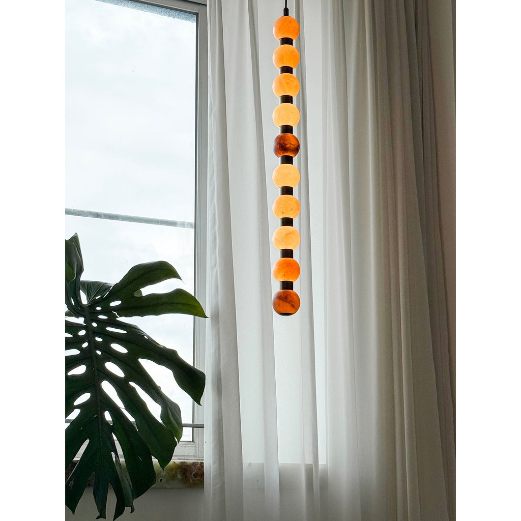 Near a monstera leaf, the upper spheres of this Clérachic pendant catch light by the window.