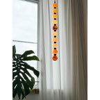 Near a monstera leaf, the upper spheres of this Clérachic pendant catch light by the window.
