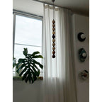 A close view shows the pale natural stone tones of this Clérachic pendant beside a wall of round discs.