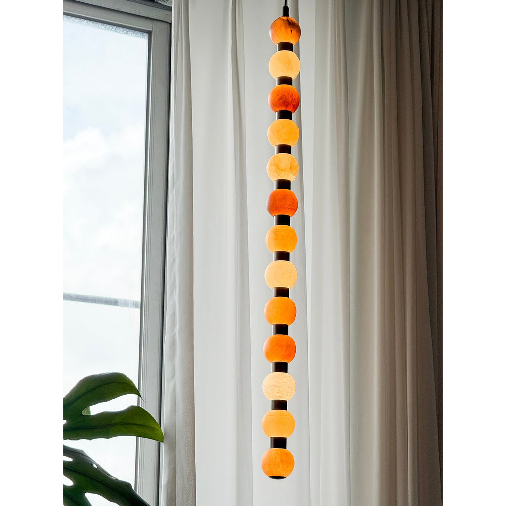 This Clérachic pendant's pale alabaster spheres hang against a bright window and sheer curtain.