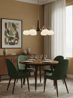 Emerald-green dining chairs surround a table lit by this Clérachic chandelier against a mustard-brown wall.