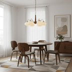Bentwood dining chairs sit beneath this Clérachic chandelier, its cream shades warm against a white wall.