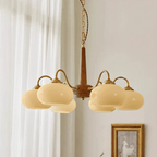 Sheer curtains and a small gilt-framed print sit beside this Clérachic chandelier's six lit cream shades.