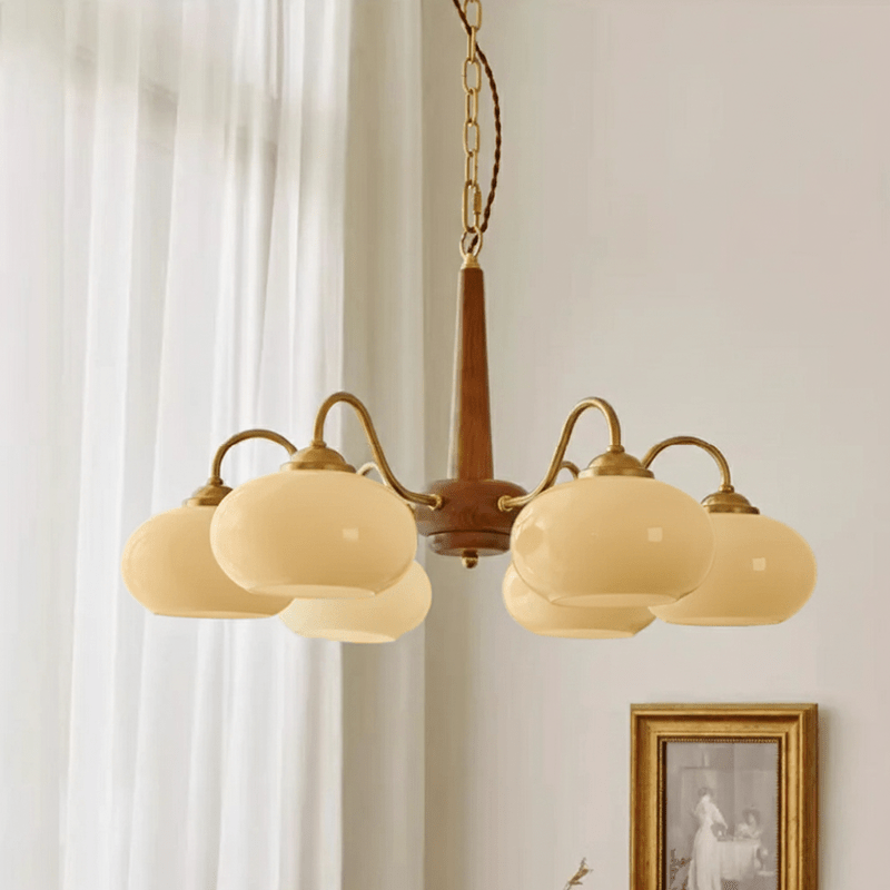 Sheer curtains and a small gilt-framed print sit beside this Clérachic chandelier's six lit cream shades.